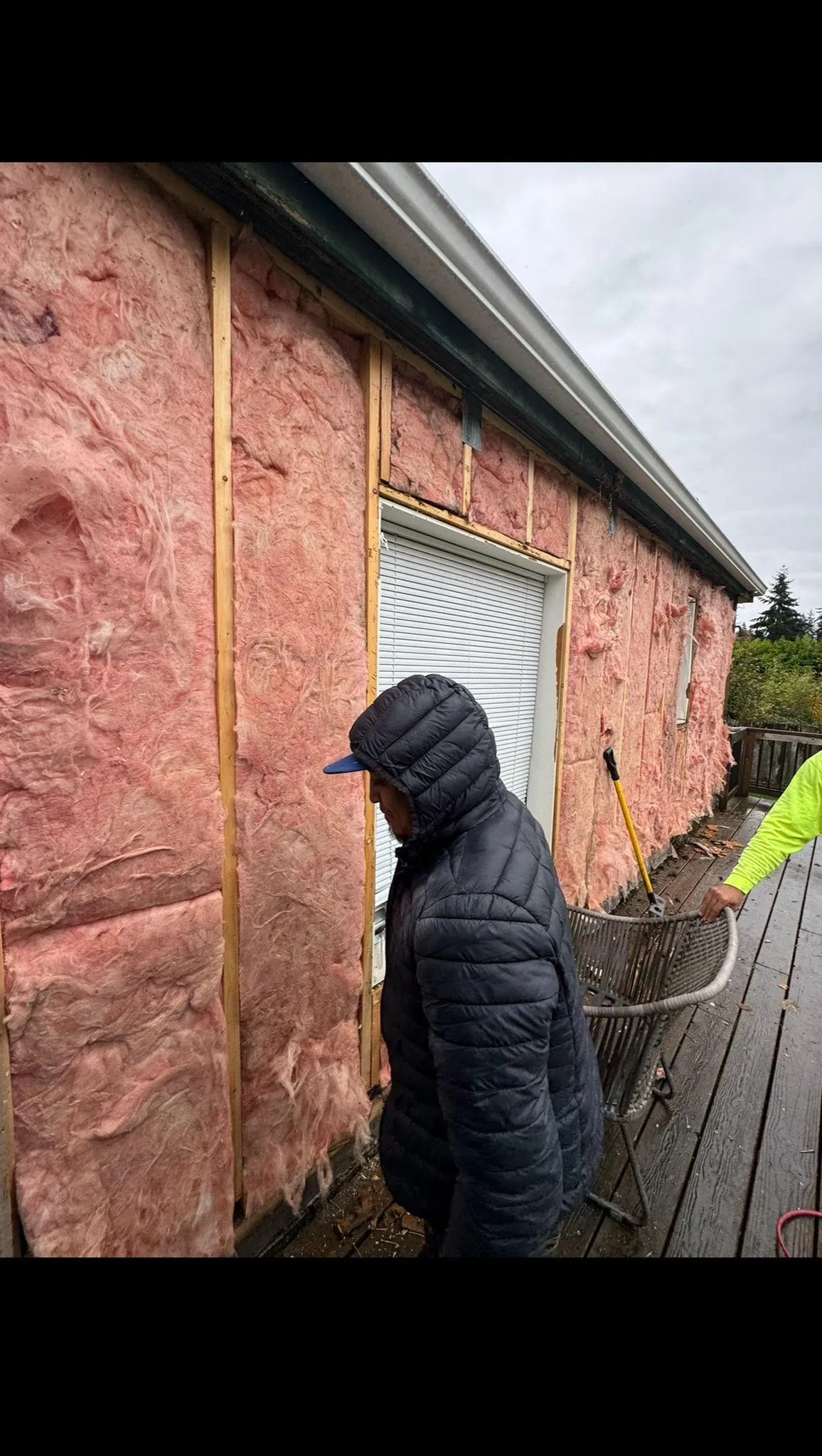Person inspecting pink insulation on a house exterior