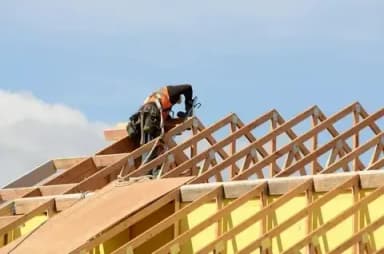 Construction worker installing roof framework on a building.