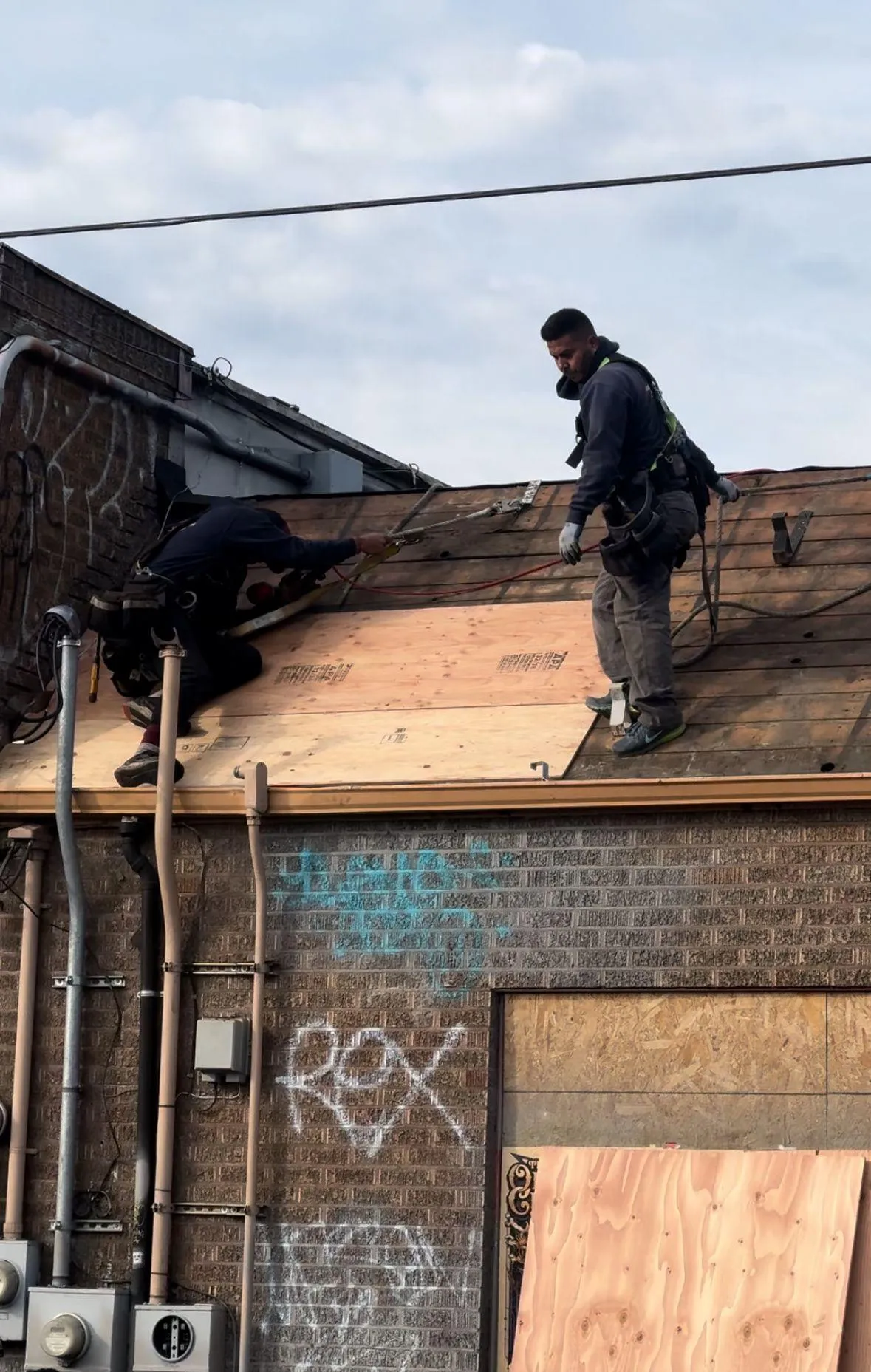 Two workers installing plywood on a roof