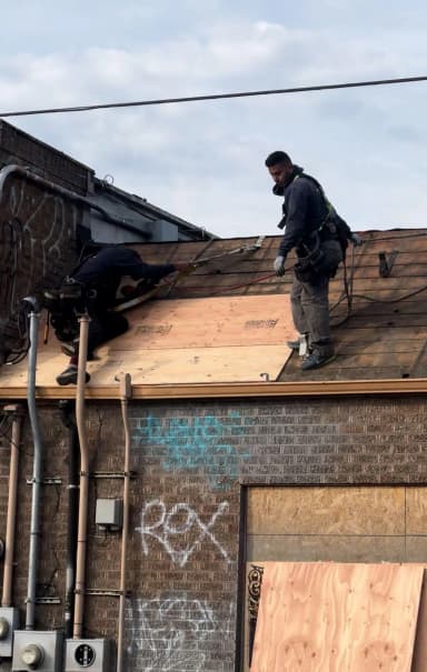Two workers installing plywood on a roof