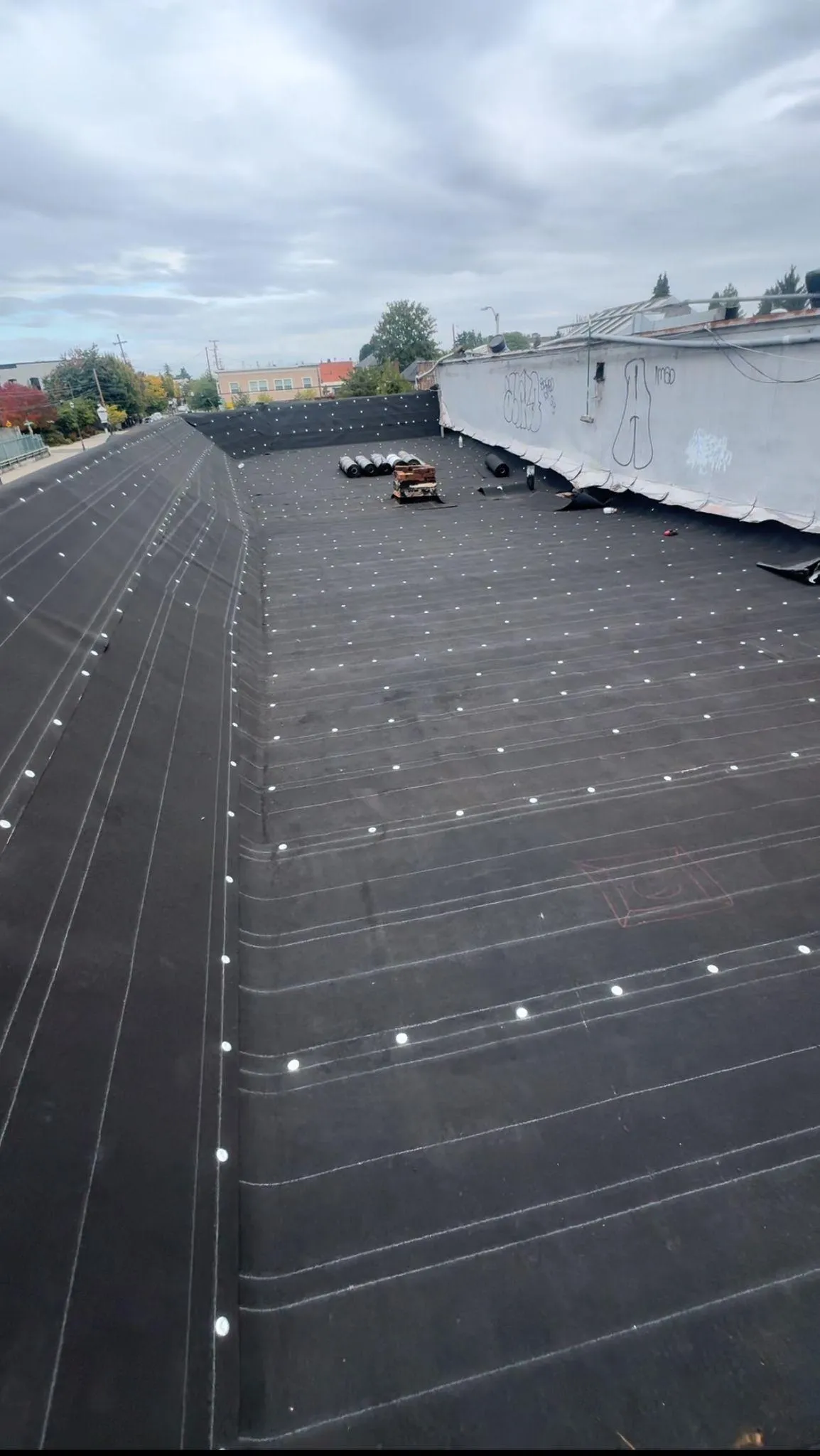 Flat roofing installation in a cloudy urban setting