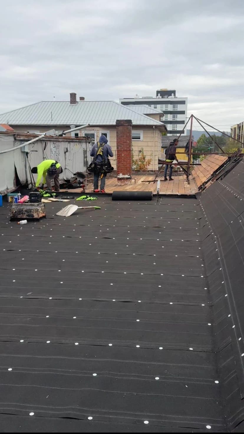 Roofing workers on a house with equipment and tools