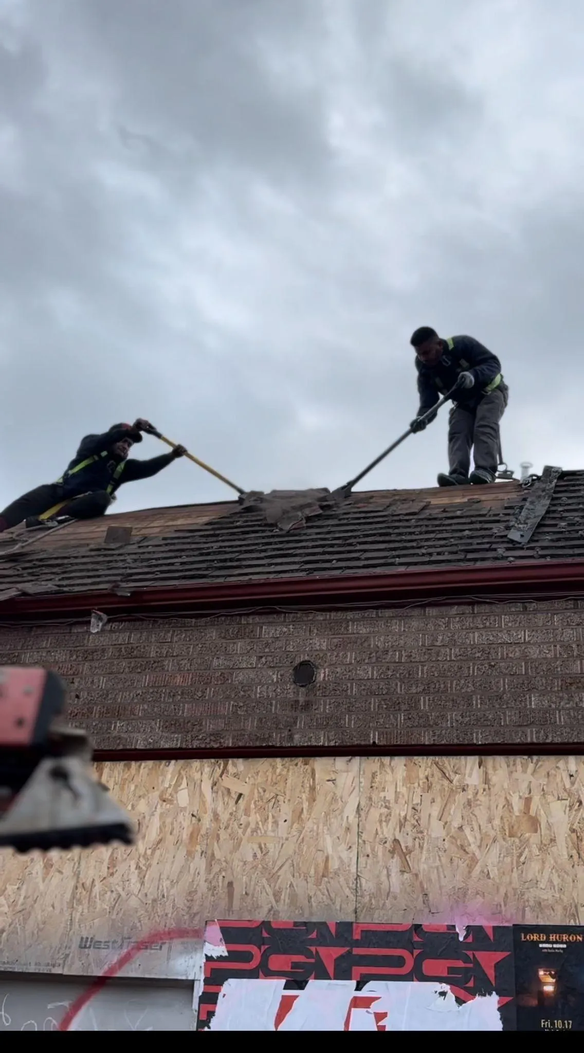 Two workers repairing a roof on a cloudy day.