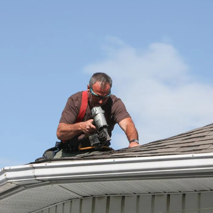 Roofer using a nail gun on a residential roof.