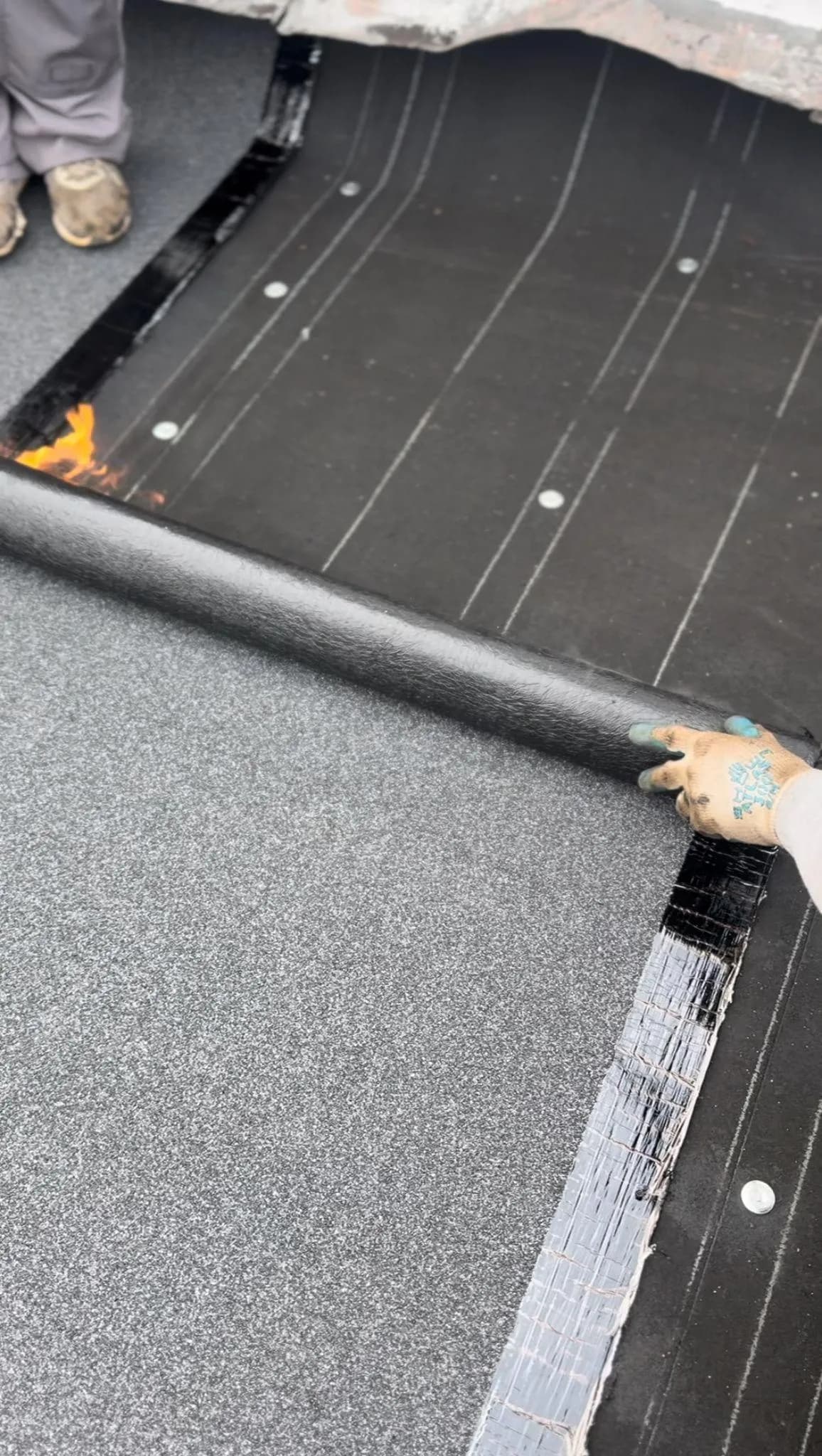 Rolling out roofing material on a black surface