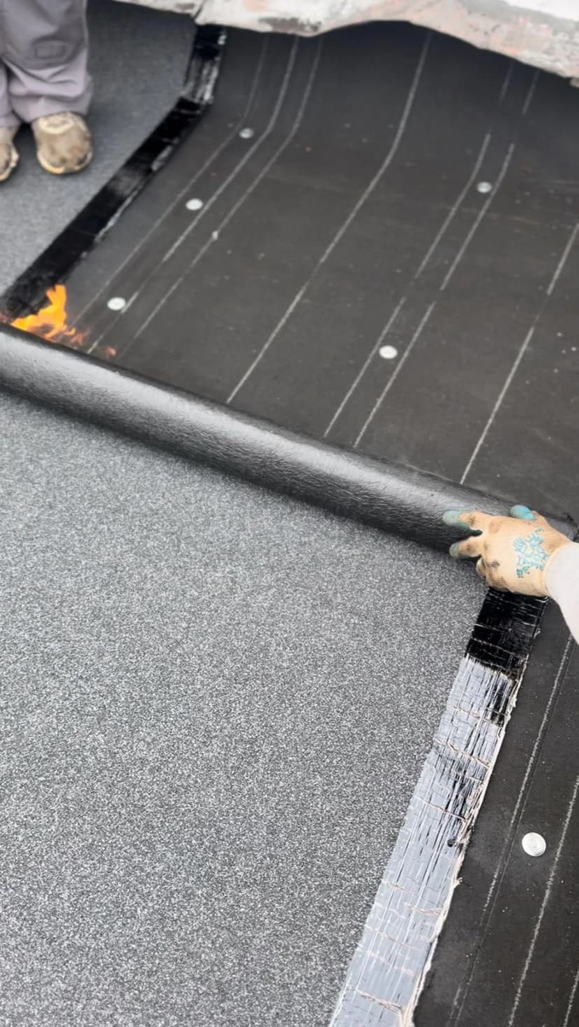 Rolling out roofing material on a black surface