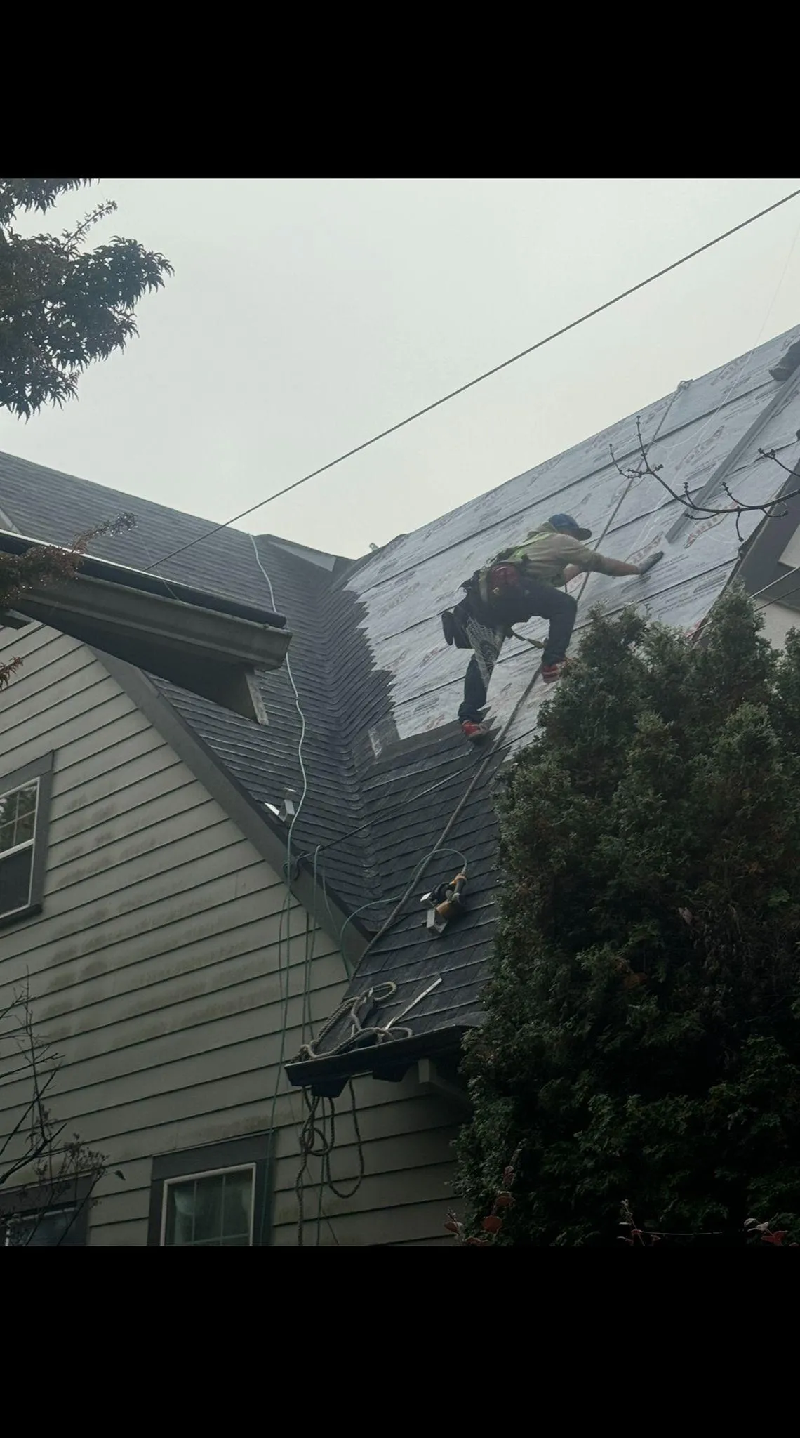 Worker repairing a roof on a house under cloudy sky